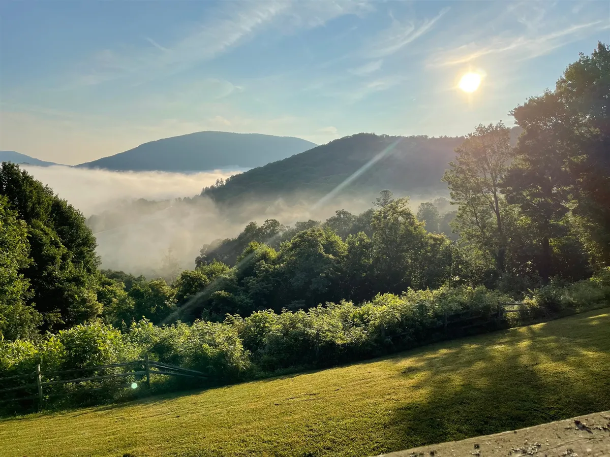 A breathtaking sunrise breaks over misty mountains and lush greenery, with hiking trails winding through the landscape and a picnic spot overlooking the panoramic vistas. The serene atmosphere is perfect for outdoor enthusiasts, families, and anyone wanting to embrace nature.