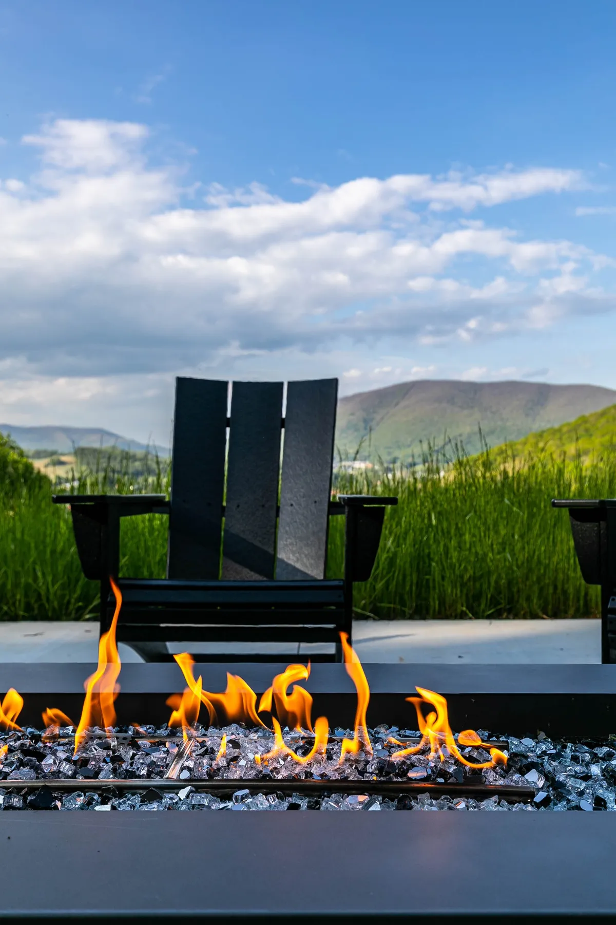 A serene fire pit area with Adirondack chairs looks out over the mountains. The fire pit invites guests to gather for stargazing, storytelling, or a cozy evening under the open sky, surrounded by nature.