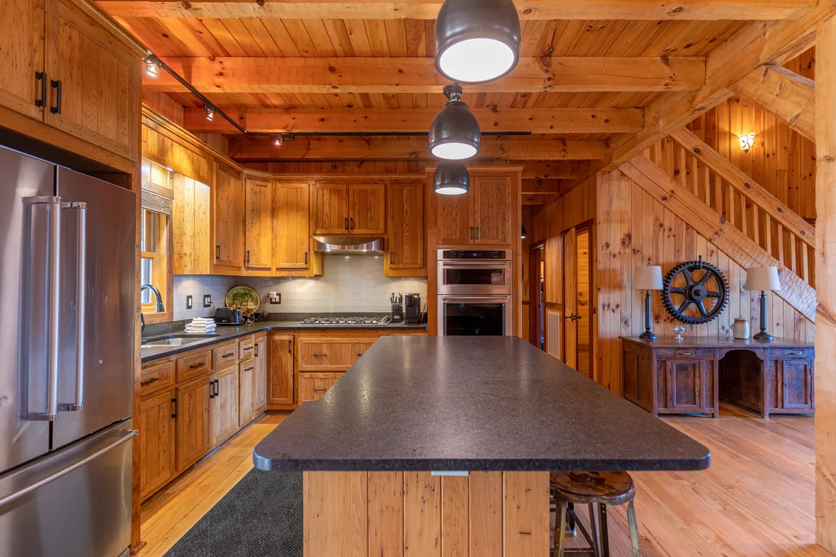 A modern, open kitchen with a large island, wooden cabinetry, gleaming stainless steel appliances, and pendant lighting. The space is designed for family gatherings and culinary creativity, with ample counter space for meal preparation.