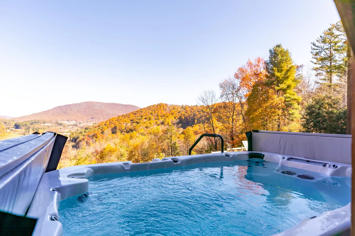 An inviting hot tub set on a wooden deck, surrounded by autumn foliage and overlooking rolling mountains. The scene feels serene and restorative, capturing the sense of post-work relaxation described in the text.